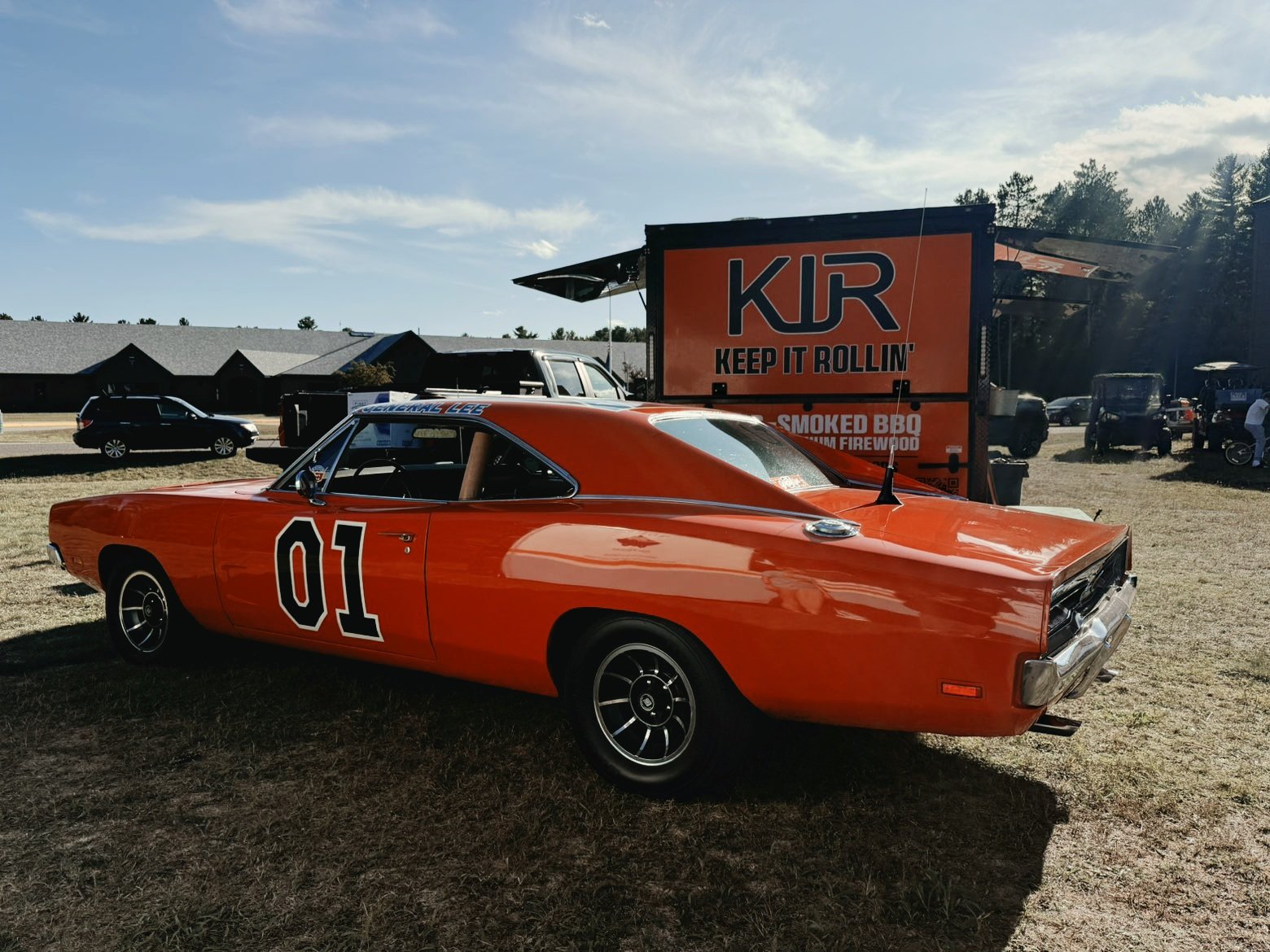 The orange KIR food trailer parked behind the General Lee car at an outdoor event