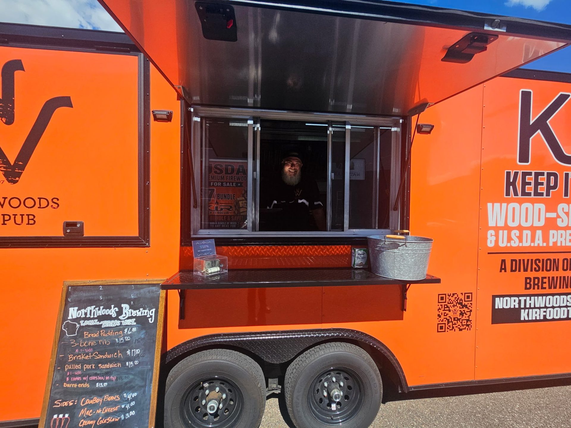 The open KIR trailer serving window beside a handwritten menu board